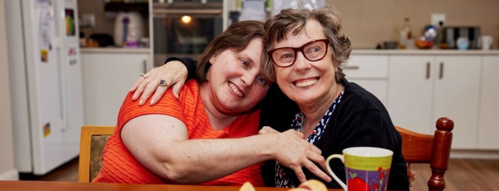 Two disabled women smiling in a kitchen
