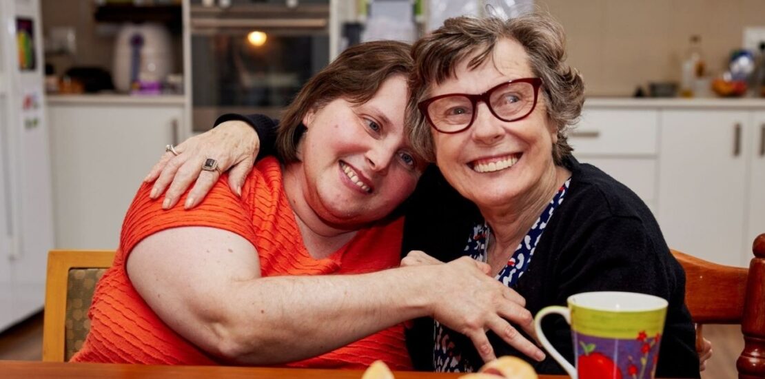 Two disabled women smiling in a kitchen