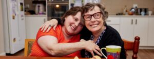 Two disabled women smiling in a kitchen